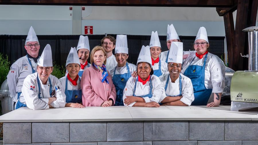 A group of people, most of whom are wearing chef uniforms, pose for a photo.