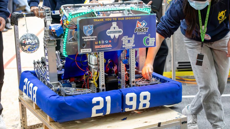 Students push a robot that has the number 2198 on it.