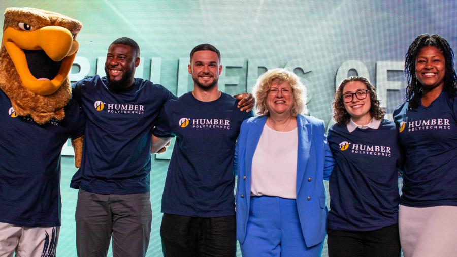 Humber President, Ann Marie Vaughan, stands with four students and the Humber Hawk mascot wearing Humber Polytechnic tshirts.