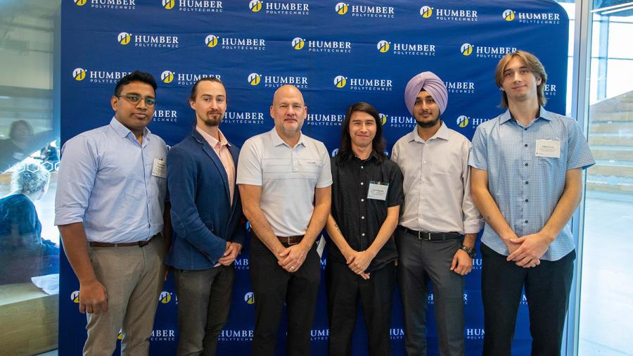 Several people stand in front of a banner with the Humber Polytechnic logo on it.