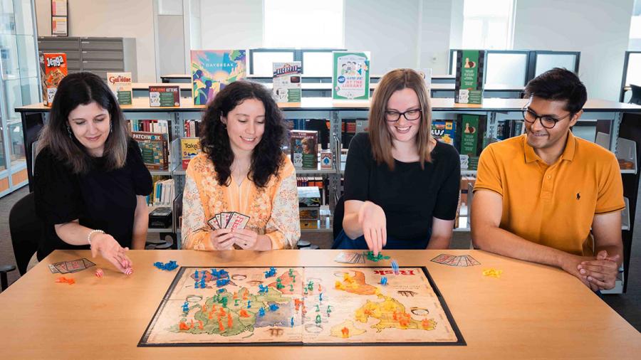 Four people are sitting at a table while playing a board game.