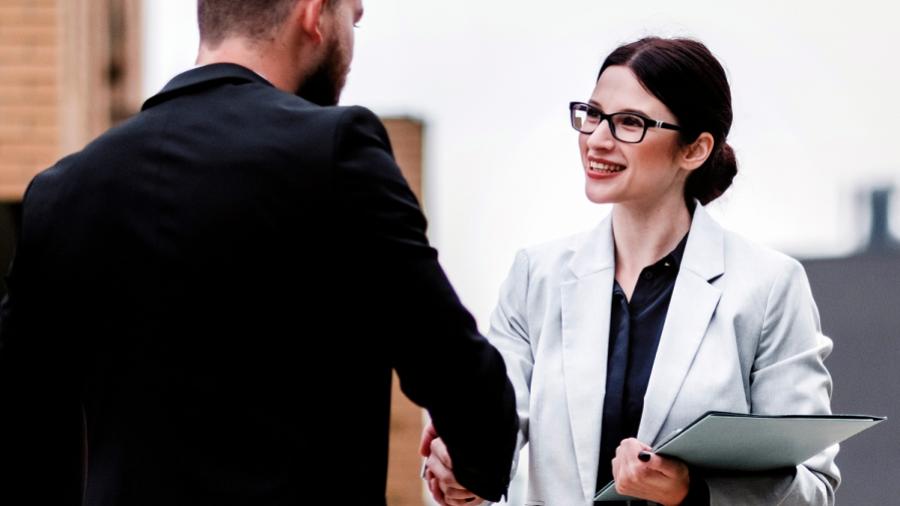 Two smiling people are shaking hands.