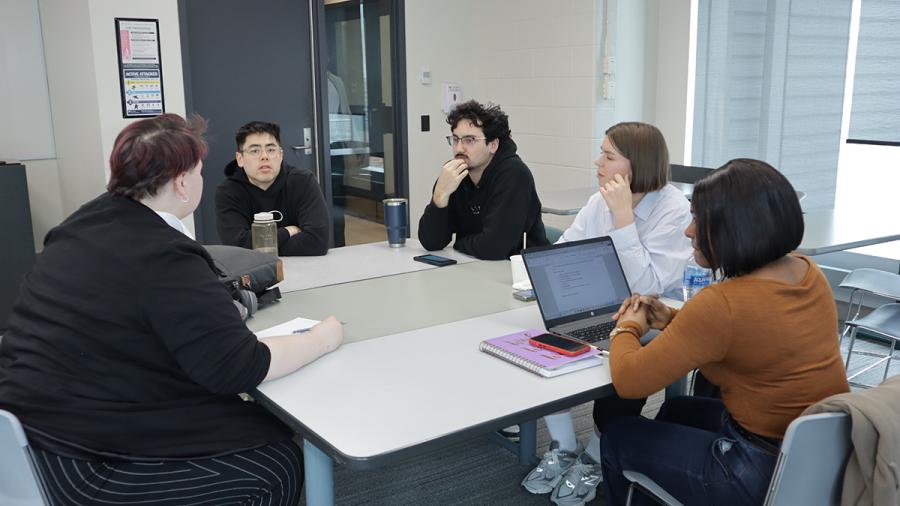 A group of people sitting around a table are having a discussion.