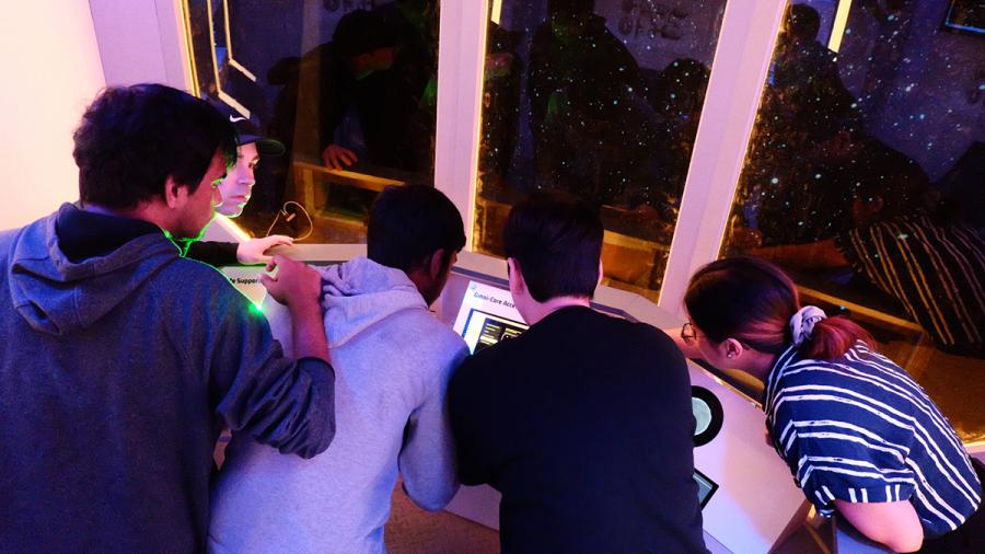 Several people are trying to solve a puzzle in an escape room.