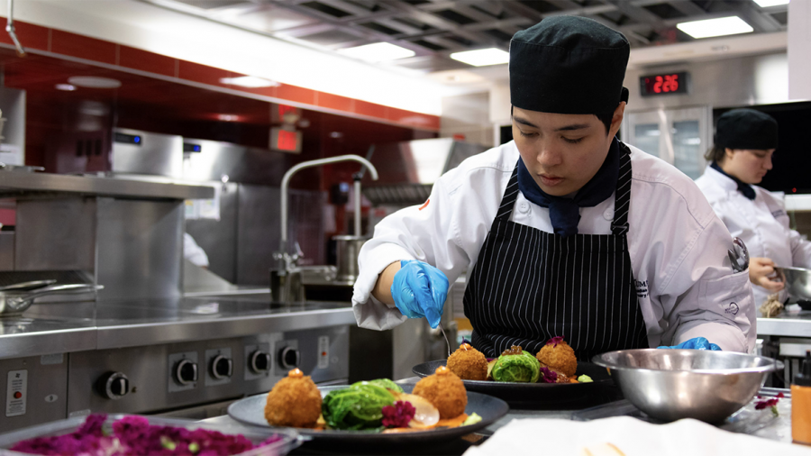 A person plates a dish while cooking in a kitchen.