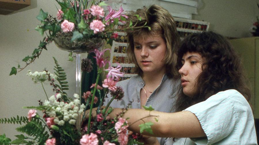 Two people are putting together a floral arrangement.