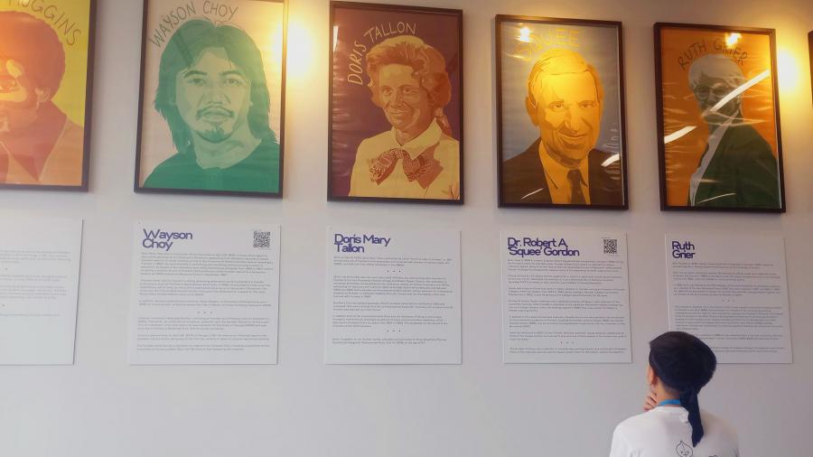 Individual looks up at framed portraits on a wall. 