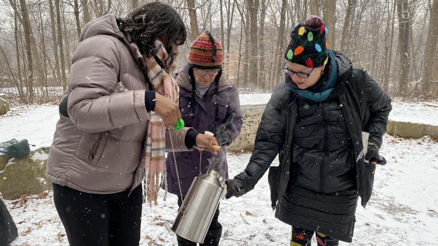 Lynn Short, Andrew Williams and Louise Zimanyi make tea in a Kelly Kettle in a snowy clearing beside the Humber River