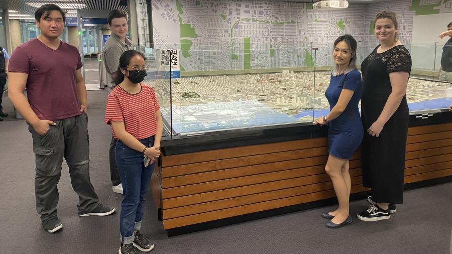 A group of five Humber College students pose with a model of the City of Toronto that’s on display at City Hall.