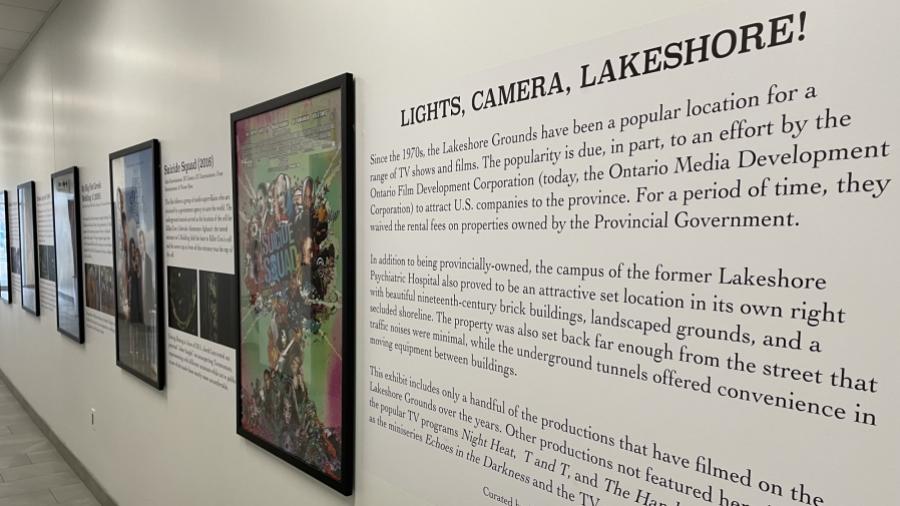 A series of framed movie posters hanging on a wall next to the words Lights, Camera, Lakeshore! There is text below those words.