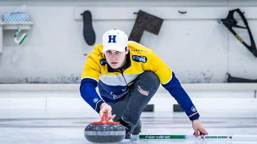 A person wearing Humber Hawks apparel is curling.