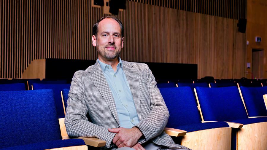 A person sits in a chair in a theatre.