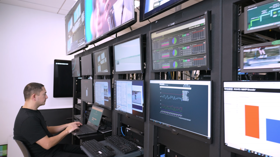 A person works on a laptop computer while sitting in front of several monitors.