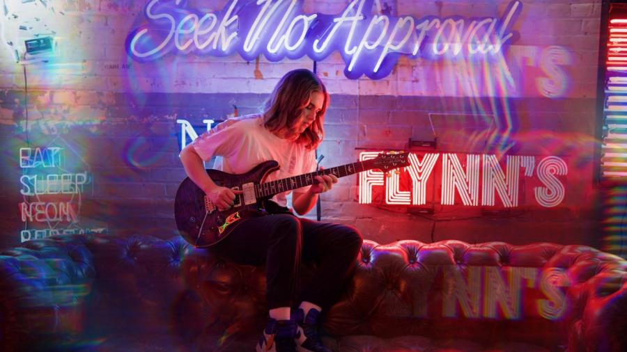Humber music student Kiana Persad plays her guitar in front of neon lights