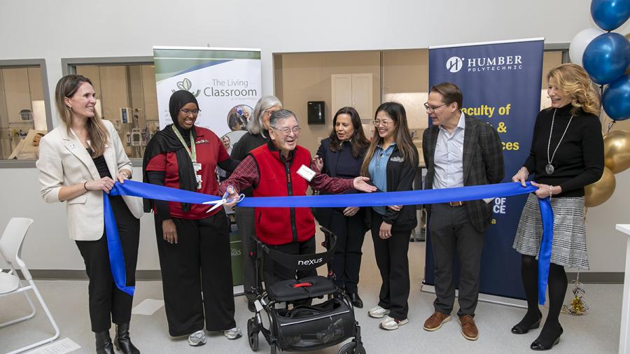 A person is getting ready to cut a ribbon with a pair of scissors as other people look on.