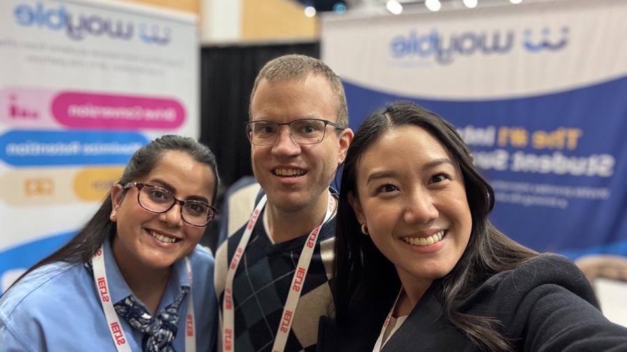Three smiling people take a selfie.