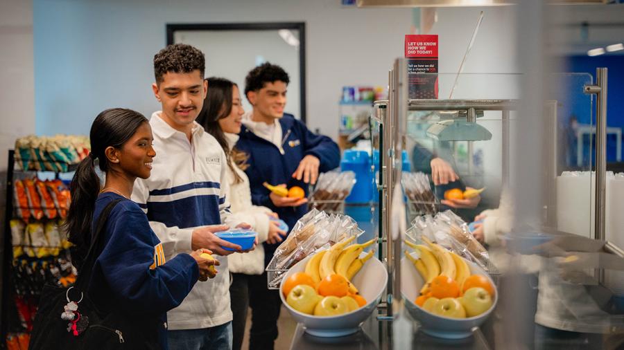 Students wait in line for food in a cafeteria.