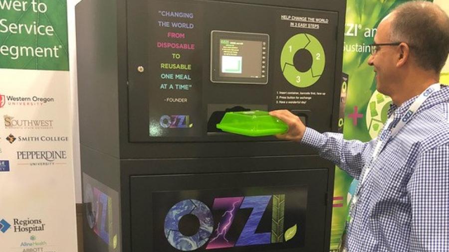 A person returns a reusable food container to a machine that collects them.