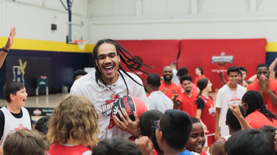 Toronto Raptor's player, Dalano Banton, celebrates with a group of kids at a basketball camp at Humber College.