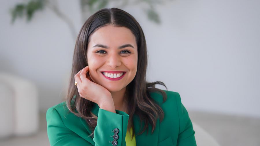 A smiling person sits on a chair.