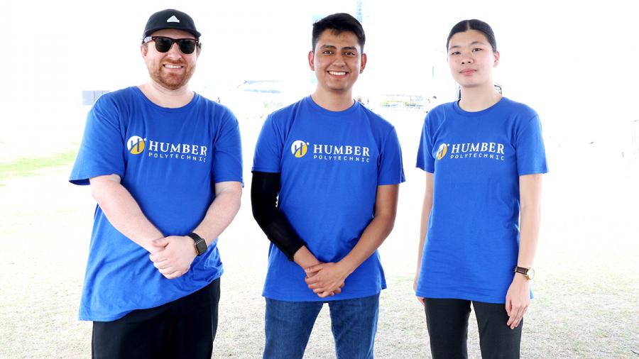 Three people wearing Humber Polytechnic tshirts stand together.
