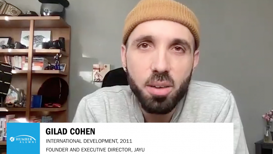 A screenshot of Gilad Cohen speaking over video call wearing a yellow beanie with his title written across the screen