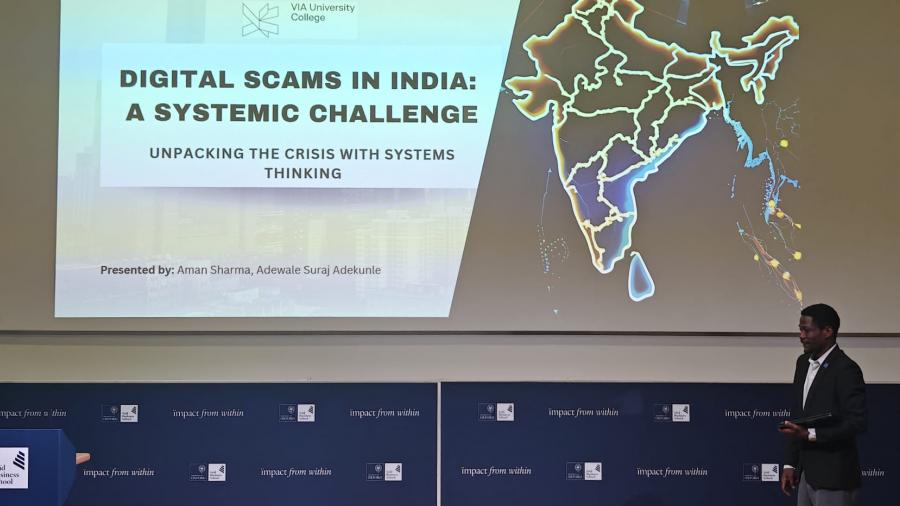 Two people stand on stage and deliver a presentation to an audience.