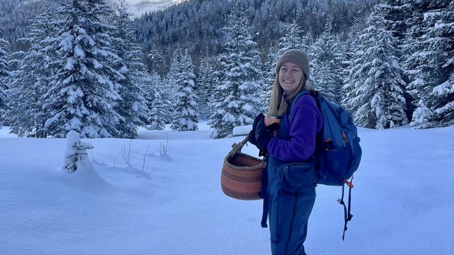 A person stands outside in a snowy forest.