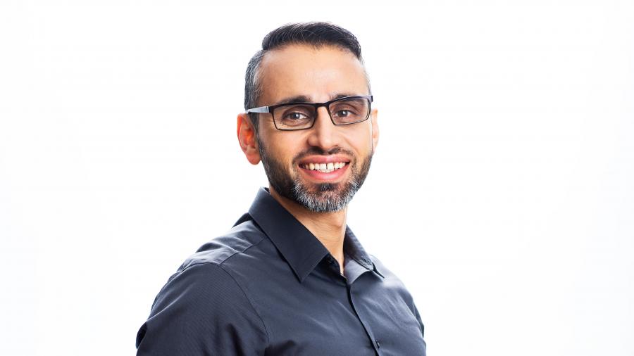 Farid Yaghini smiles in a headshot against a white background. The headshot is casual but professional