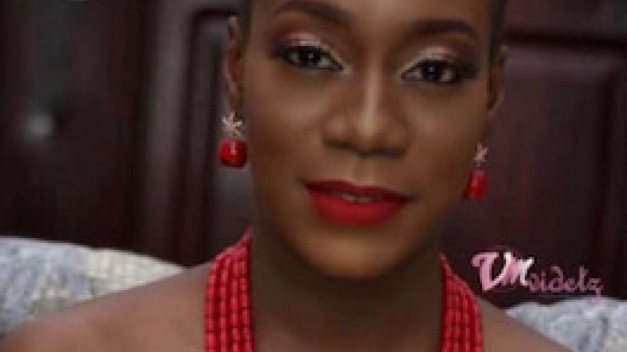 Olatoke Adeboboye smiles softly at the camera in a closeup, wearing a red necklace and off-the shoulder white top.