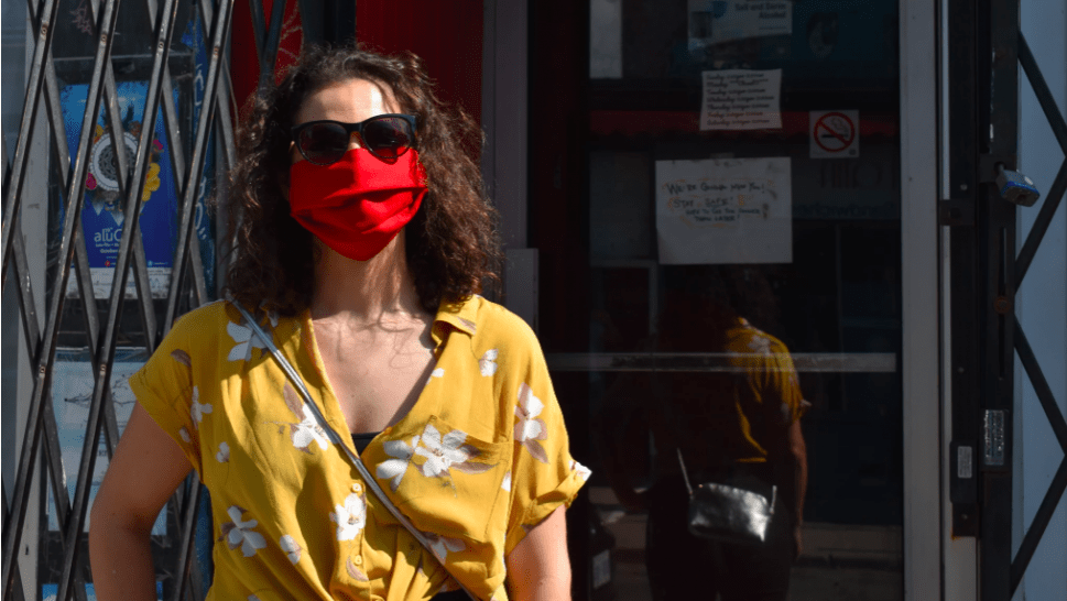 A Kensington Market visitor colour coordinates their red mask with their yellow shirt