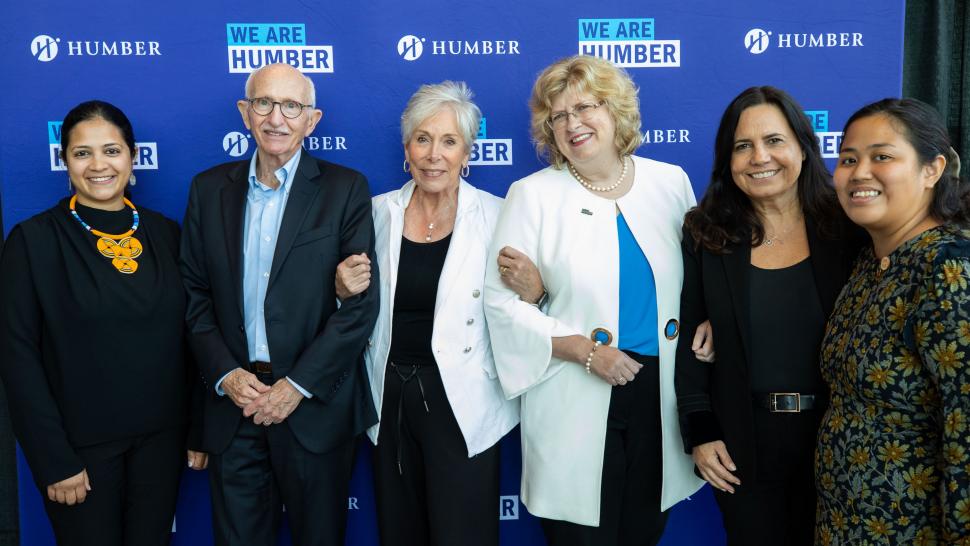 Six smiling people stand in a row in front of a blue backdrop that reads Humber and We Are Humber.