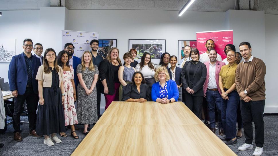 Humber and The King’s Trust Canada have partnered to develop state-of-the-art skills courses designed to provide young people with the skills needed for the job market. A group of people stand around a table that two people are seated at.