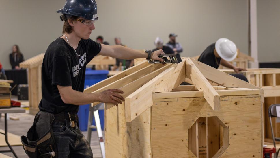 Humber Polytechnic students took part in the Skills Ontario 2025 competition held May 5 to May 7 at the Toronto Congress Centre. A person wearing a hardhat uses a level on a wooden structure.