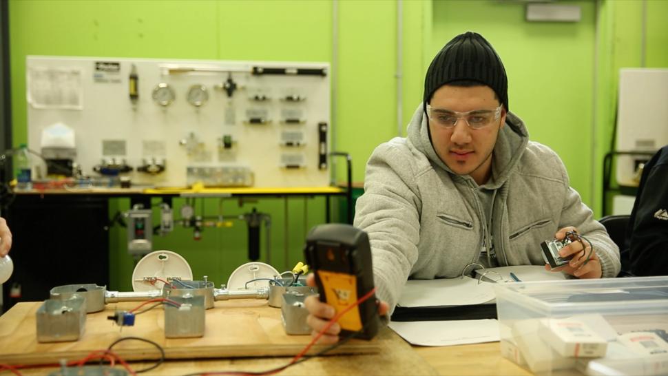 An applied research student works at a desk covered in tech devices