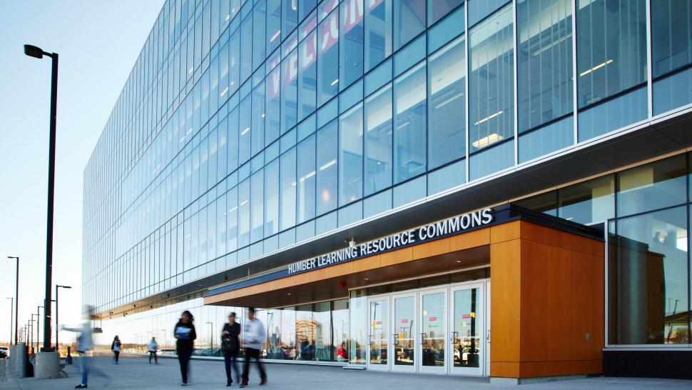 People stand outside a building that has a sign reading Humber Learning Resource Commons.