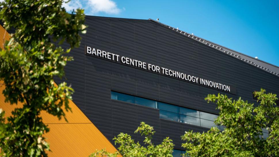 The Barrett CTI building, which is dark grey with yellow accents, shot from below in front of a blue sky