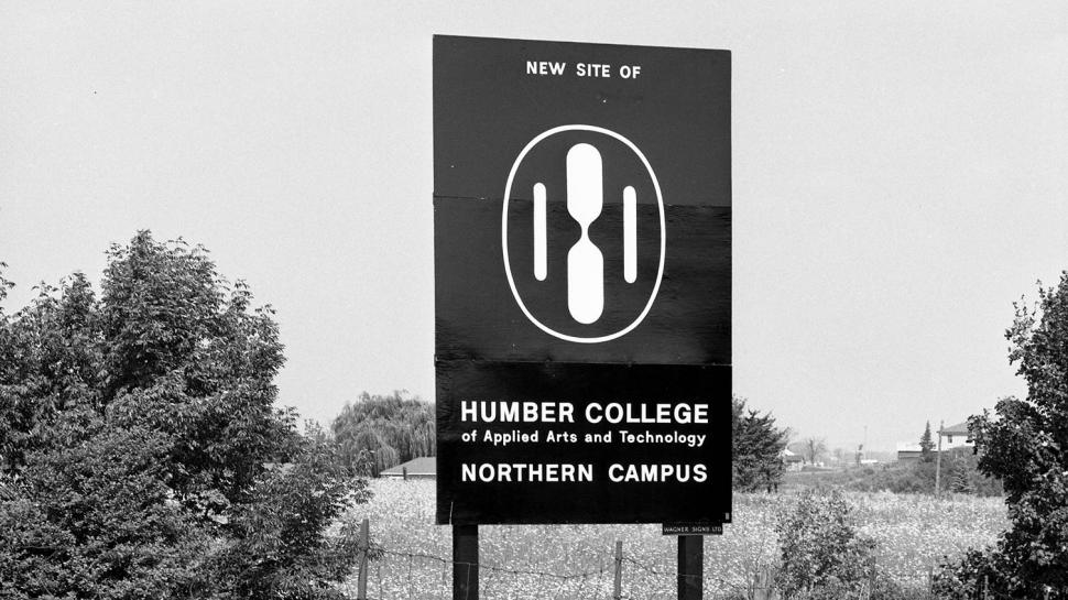 A black and white photo of the first Humber College logo on a billboard that reads New Site of Humber College Northern Campus.