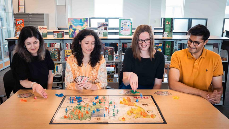 The Humber Polytechnic Library has expanded its collection this summer with a playful new addition – board games. Four people are sitting at a table while playing a board game.