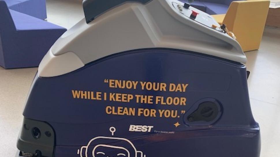 A cleaning machine with the 英雄联盟竞猜线上入口靠谱 College logo with the words Enjoy your day while I keep the floor clean for you on the side.