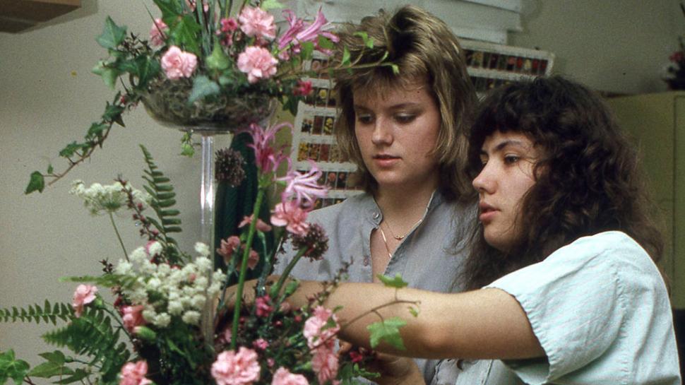 Two people are putting together a floral arrangement.