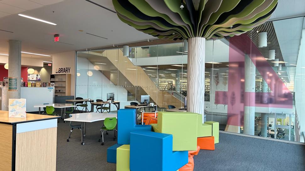  An area with brightly coloured seats, books and an artificial tree.