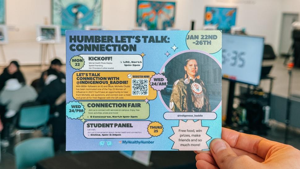 A hand holds up a card with information on it about Humber Let’s Talk.