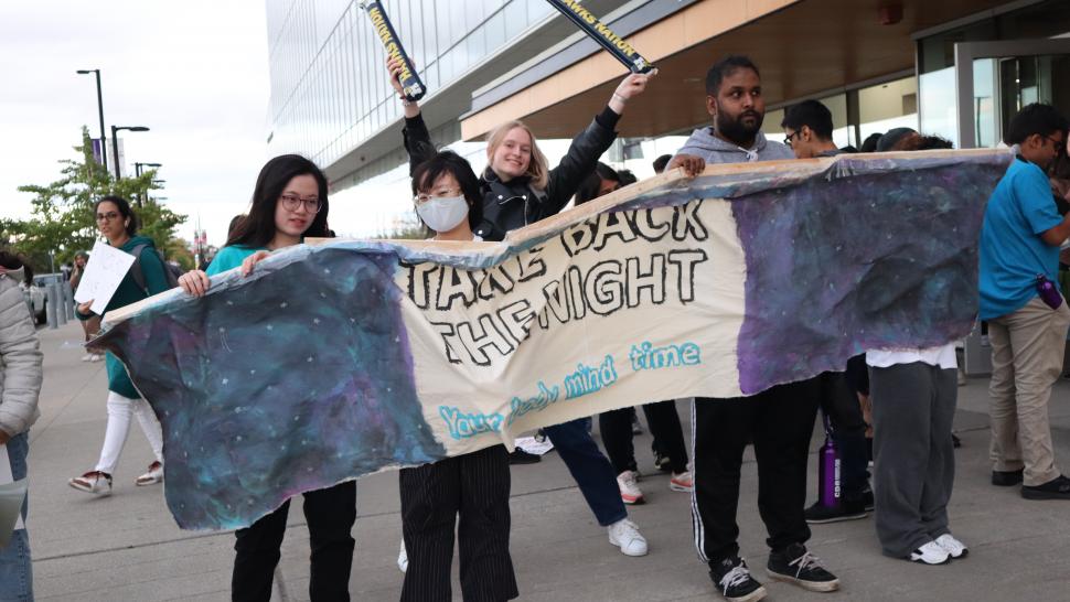 Several people hold up a banner that reads Take Back the Night outside of the Humber College’s Learning Resource Commons.