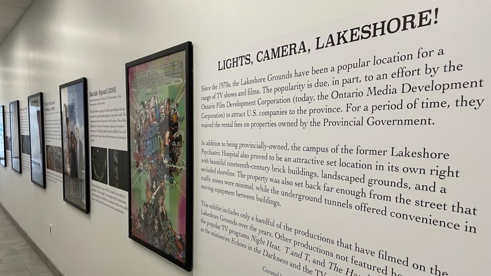 A series of framed movie posters hanging on a wall next to the words Lights, Camera, Lakeshore! There is text below those words.
