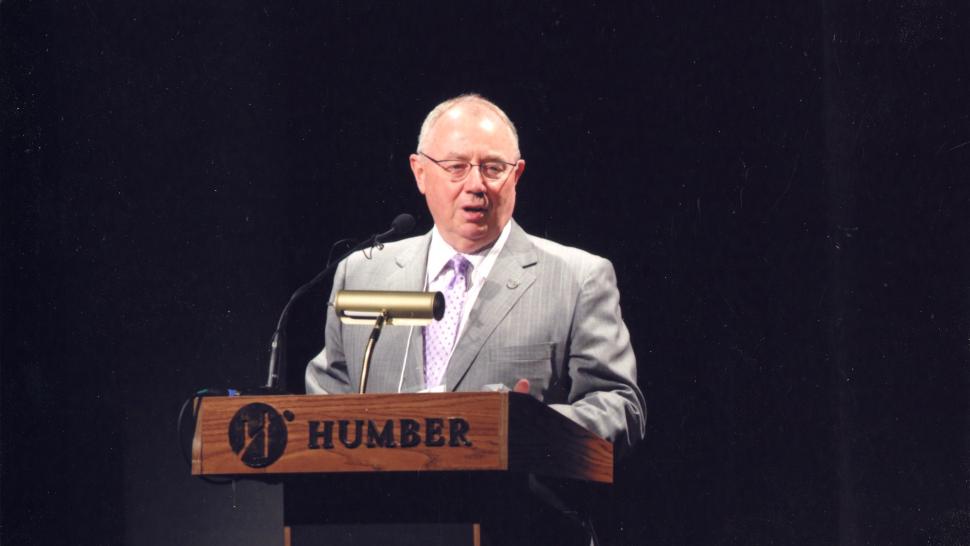 A person stands at a podium that has the word Humber on it.
