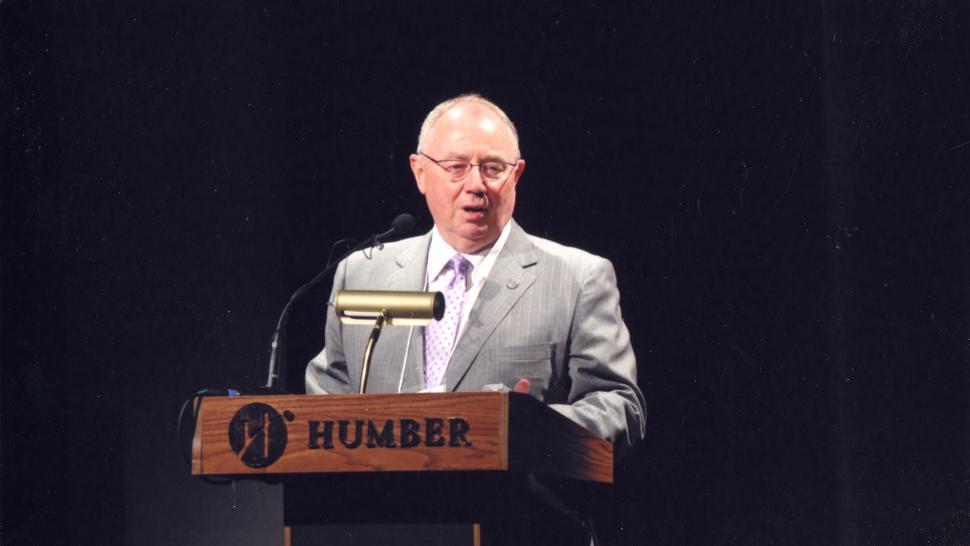 The Humber Archives has received a donation of photographs from John Davies’ time as Humber’s President. A person stands at a podium that has the word Humber on it.