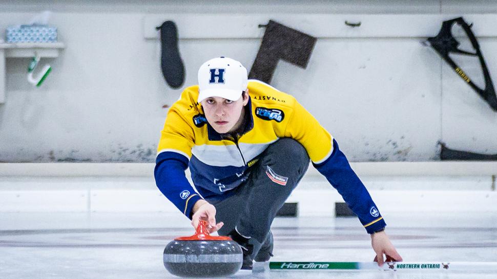 A person wearing Humber Hawks apparel is curling.