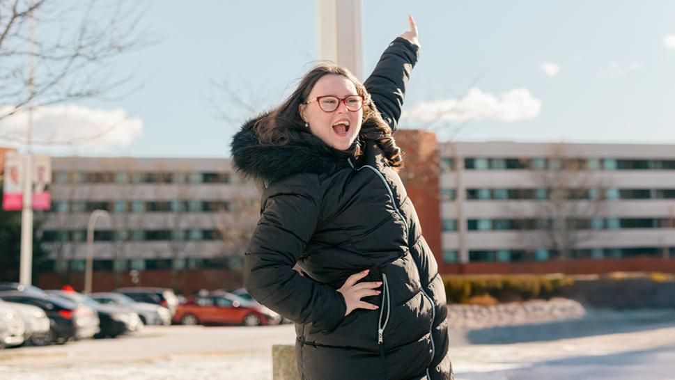 A smiling person points towards a banner with their picture on it.