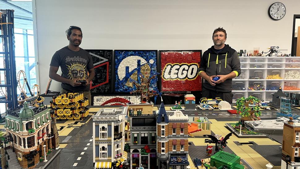 Two people stand amongst a miniature city made of LEGO.